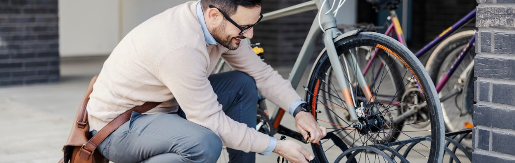 Ein Mann schließt sein Fahrrad auf der Straße ab.