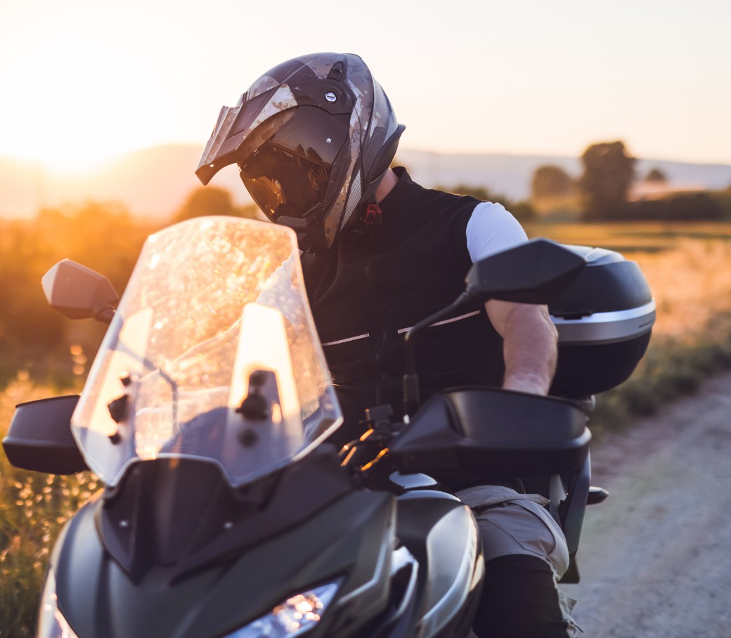 Motorradfahrer macht während einer Fahrt auf der Landstraße bei Sonnenuntergang eine Pause.