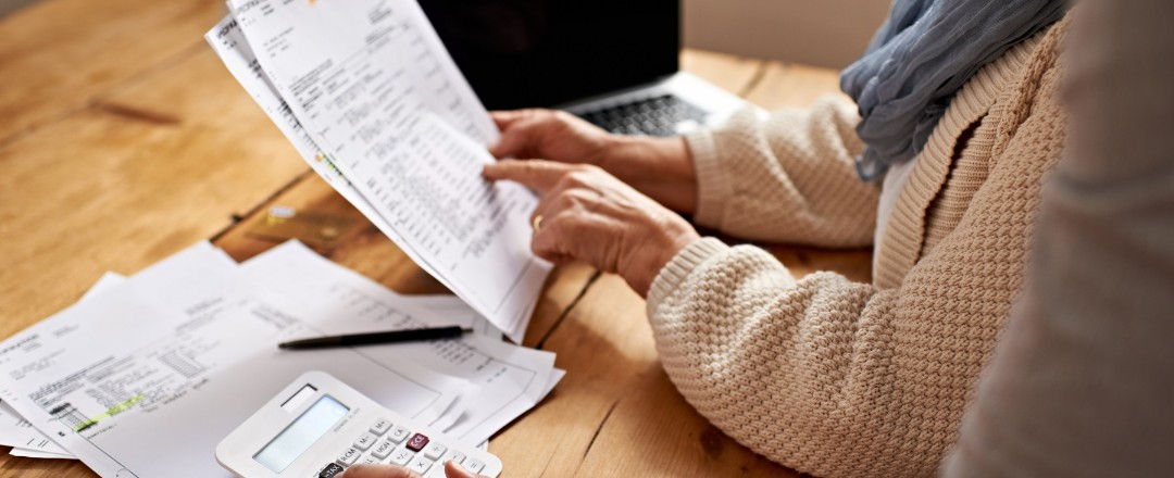 Beschnittene Ansicht einer älteren Frau, die von ihrer Tochter Hilfe bei ihren Finanzen erhält.