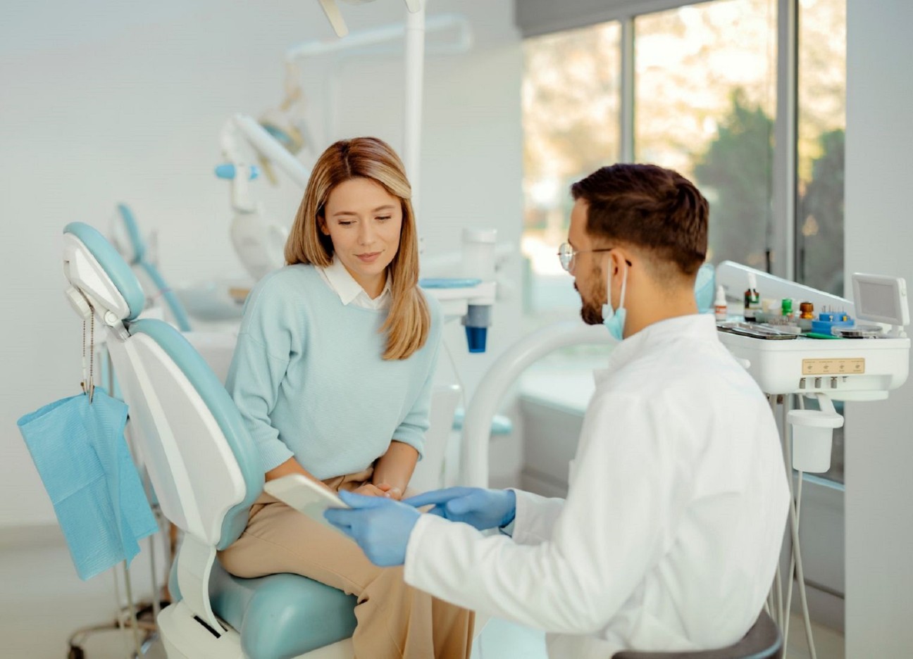 Patientin sitzt im Behandlungsstuhl beim Zahnarzt und bespricht Kostenplan 