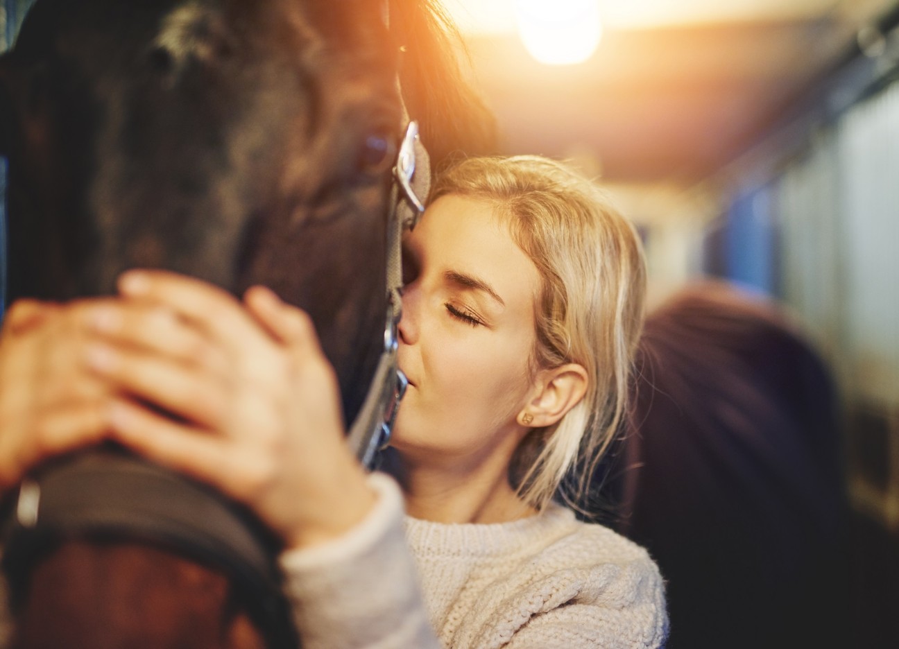 Junge Frau umarmt ihr Pferd im Stall