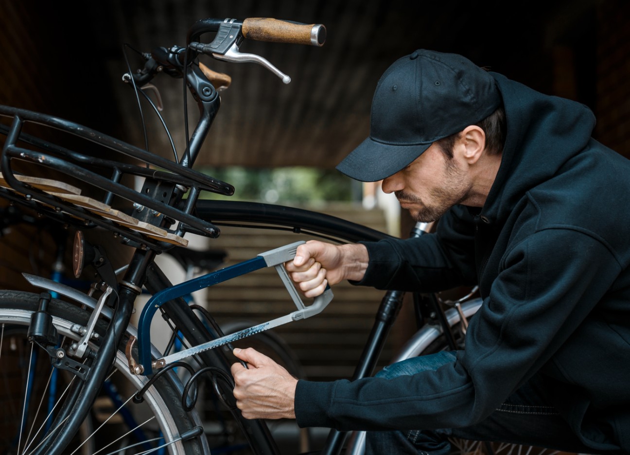 Ein Dieb sägt das Bügelschloss auf, mit dem ein Fahrrad gesichert ist. 