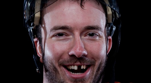 Eishockeyspieler mit fehlenden Schneidezähnen posiert lachend