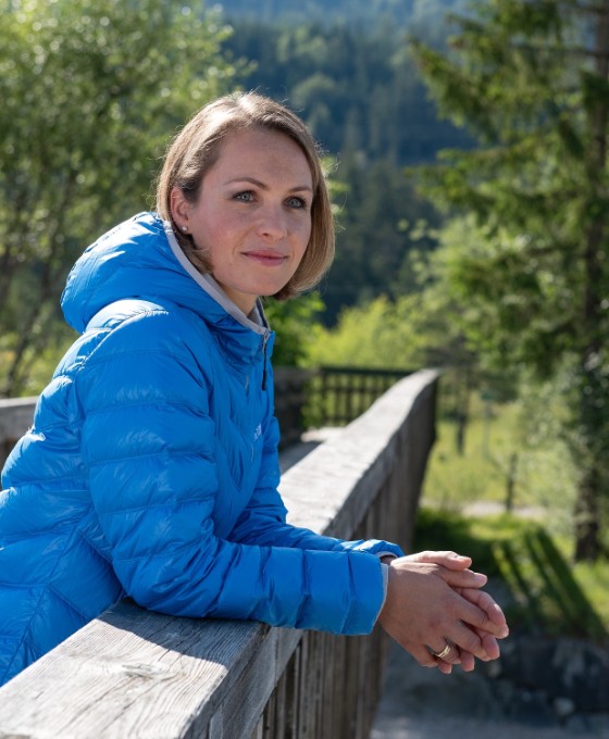 Magdalena Neuer steht auf einer Holzbrücke im Grünen und schaut in die Ferne.