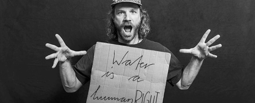 Bild von einem Mann der ein Schild mit Aufschrift "Water is a human right" hält.