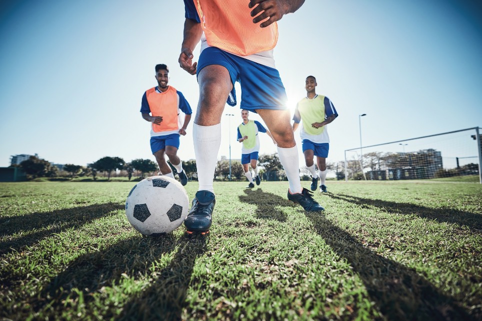 Fußballspiel von Männern, Beine mit Sonne im Hintergrund