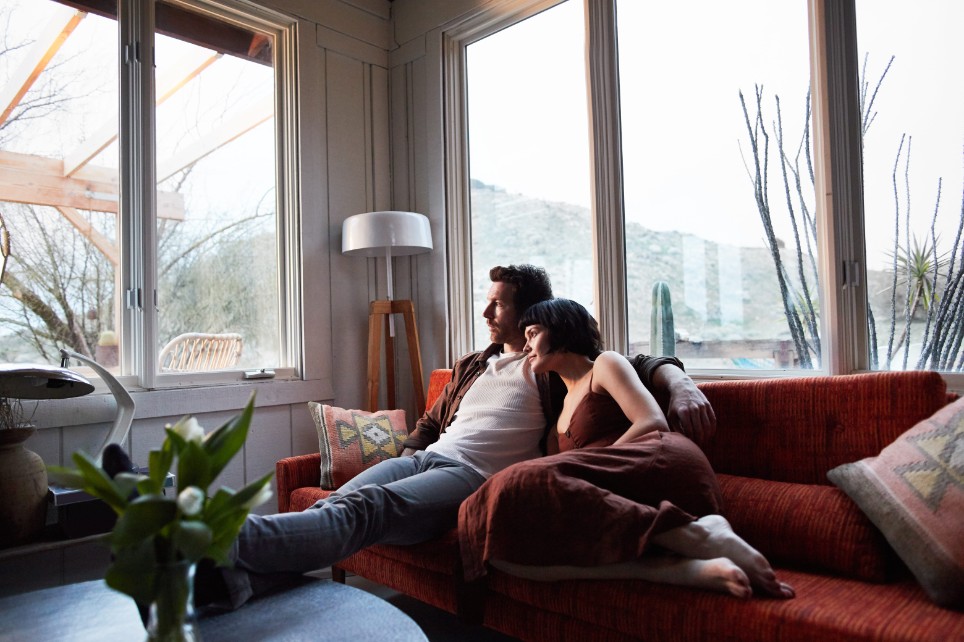 Ein Mann und eine Frau kuscheln sich auf dem Sofa aneinander.