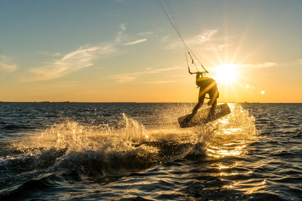 Eine Person betreibt Kitesurfen im Sonnenuntergang.