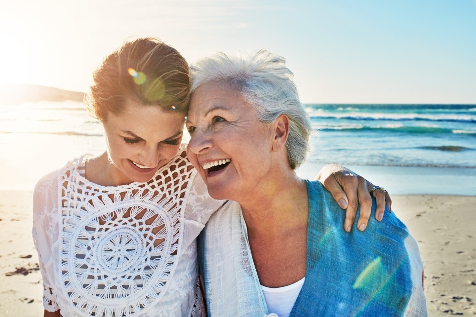 Mutter und erwachsene Tochter lachen am Strand